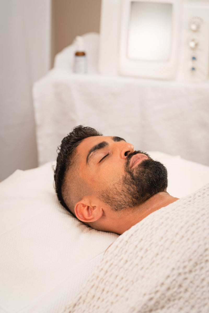 Ein Mann liegt mit einem weißen Stirnband auf einer Behandlungsliege.